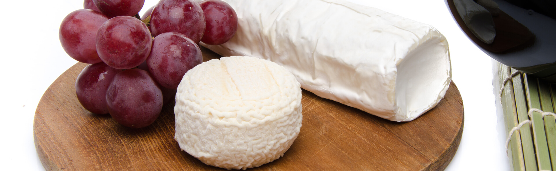 Photo of Holy Goat cheese and grapes on a wooden cutting board.